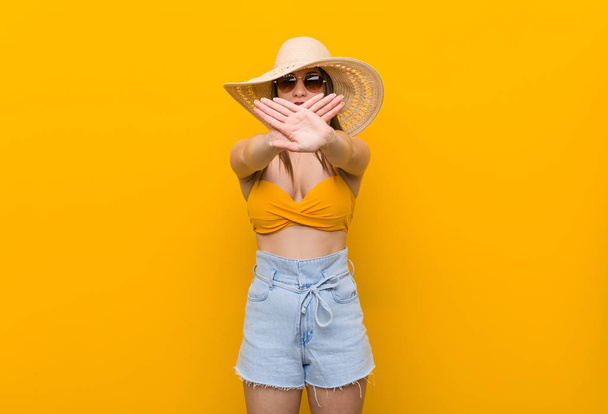 Mujer caucásica joven con un sombrero de paja, mirada de verano haciendo un gesto de negación
 - Foto, imagen