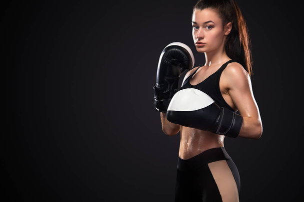 Woman boxer in boxing gloves on black background. Boxing and fitness concept. - Photo, image