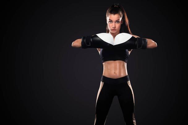 Mujer boxeadora con guantes de boxeo sobre fondo negro. Concepto de boxeo y fitness
. - Foto, Imagen