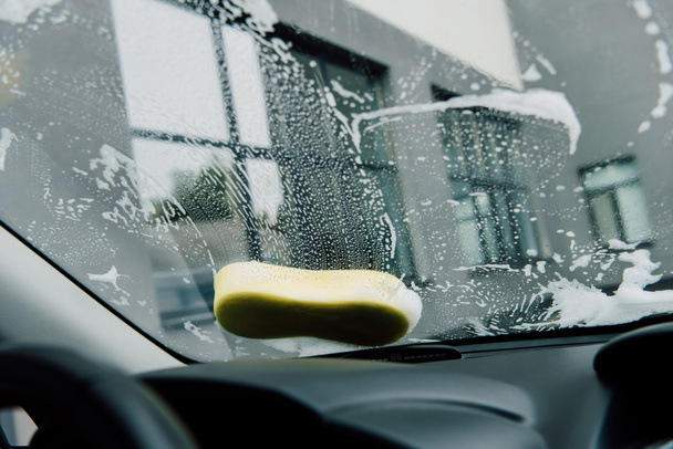 éponge jaune humide sur le pare-brise de la voiture près du bâtiment
  - Photo, image