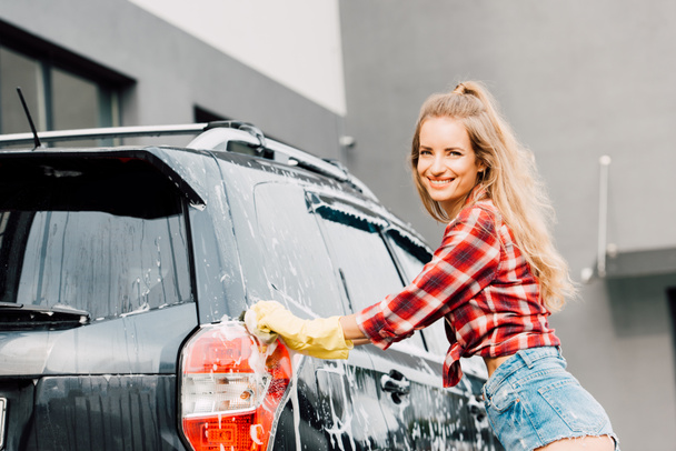 chica feliz en guantes de látex lavado de automóviles en espuma
  - Foto, Imagen