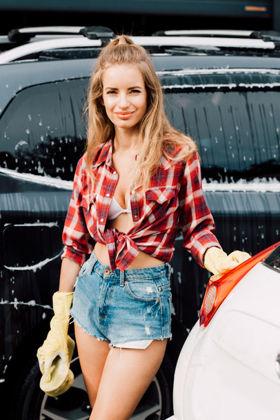 happy young woman in latex gloves standing near cars  - Foto, Imagem