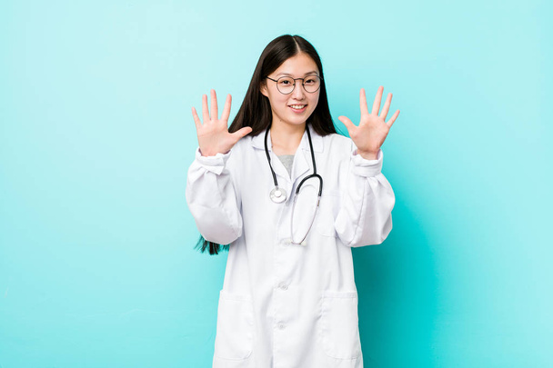 Joven doctora china mostrando el número diez con las manos
. - Foto, Imagen