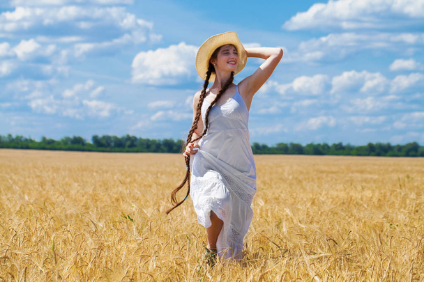 Young brunette woman in white dress walking in a wheat field - Fotografie, Obrázek