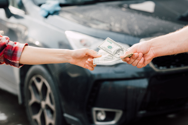 vágott kilátás az ember, amely pénzt a nő közelében autó  - Fotó, kép