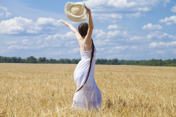 Young woman in white dress posing against the blue sky in a whea - Foto, Imagen