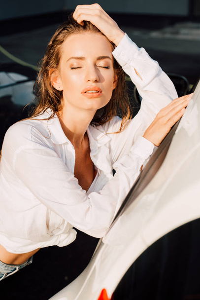 attractive woman closed eyes while standing near white car - Foto, Imagem