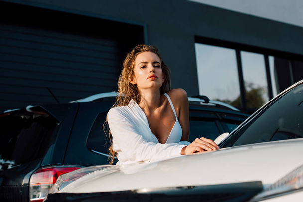 カメラ現代の白い車と建物を見てセクシーな若い女性の低角度ビュー  - 写真・画像