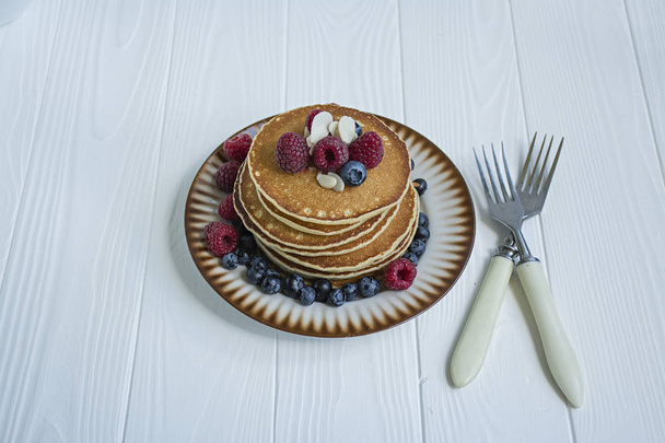 Klassieke Amerikaanse pannenkoeken met verse bessen op een blauwe houten achtergrond. Pannenkoeken met fruit. Zomer zelf gemaakt ontbijt. Ruimte voor tekst. - Foto, afbeelding