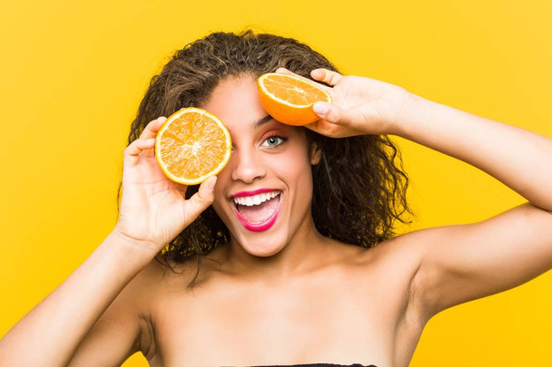 グレープフルーツを持つ若いアフリカ系アメリカ人の美しくメイクアップ女性のクローズアップ - 写真・画像