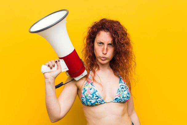 Young caucasian redhead woman holding a megaphone - 写真・画像