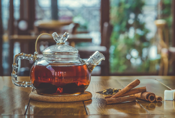 tea with cinnamon in a teapot on a wooden table. - Photo, Image