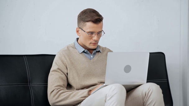 homme souriant dans des lunettes en utilisant un ordinateur portable
  - Séquence, vidéo