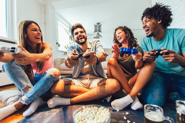 Group of friends play video games together at home, having fun. - Foto, Imagen