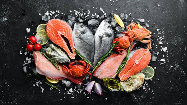 Seafood: Dorado, salmon, crab, grouper, oysters. On a black stone background. Top view. Free space for your text. - Photo, Image
