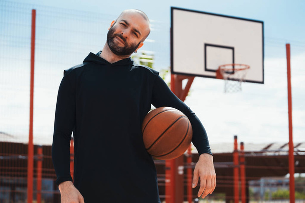 Attractive man on basketball court on basketball hoop and board background. - Foto, Imagem