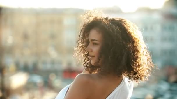 Una joven atractiva mujer con el pelo rizado coqueteando con alguien en un fondo urbano
 - Metraje, vídeo