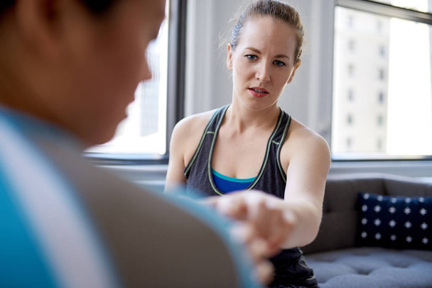 Caucasian woman physiotherapist talking to a mid-adult chinese female patient and taking notes on a tablet during a fitness evaluation consultation - 写真・画像