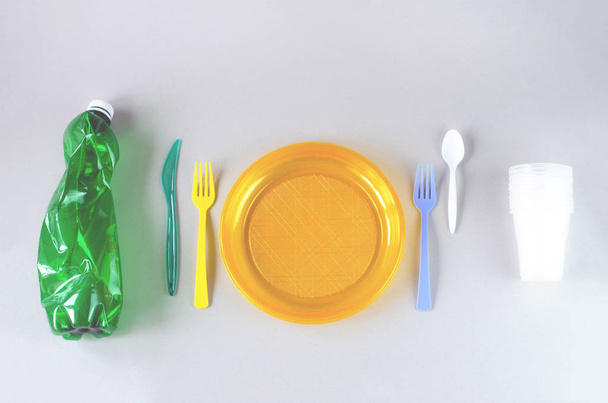 Plastic utensils and plastic bag on a gray background.  - Фото, изображение