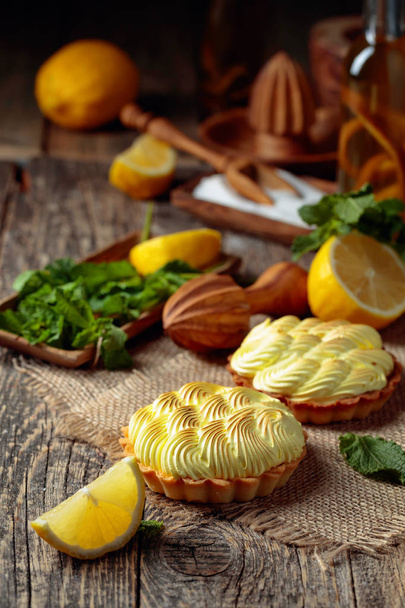 Tartlets with lemon cream and mint on a old wooden table.  - Фото, изображение