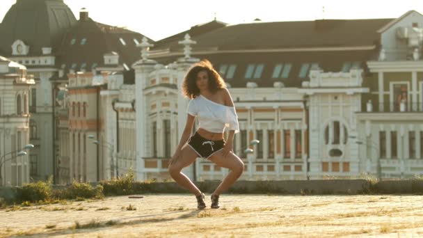 A young woman with long legs in small shorts performing attractive dancing on the roof - go down and spreading her legs- bright sunset - Footage, Video