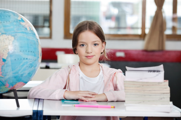Schoolgirl Sitting At Desk With Globe And Stack Of Books - Photo, image