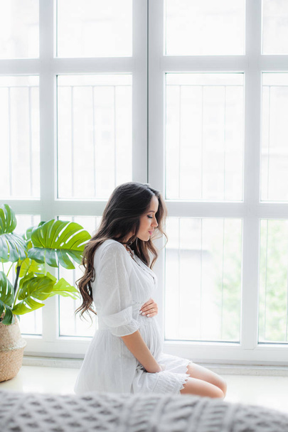 Young beautiful pregnant woman in white dress - Fotografie, Obrázek