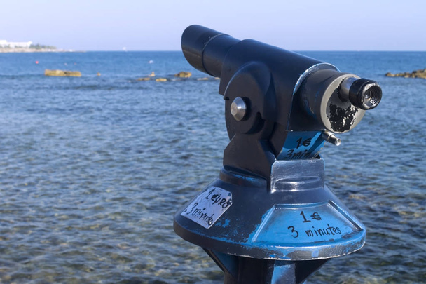 Close-up of a coin operated tourist telescope in front of the Mediterranean sea at the Paphos seaside on a sunny summer day - Photo, image