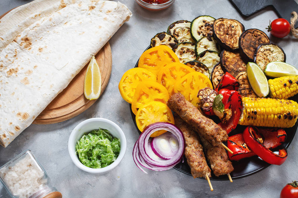 Assorted delicious grilled vegetables and meat on a concrete background. Summer food. - 写真・画像