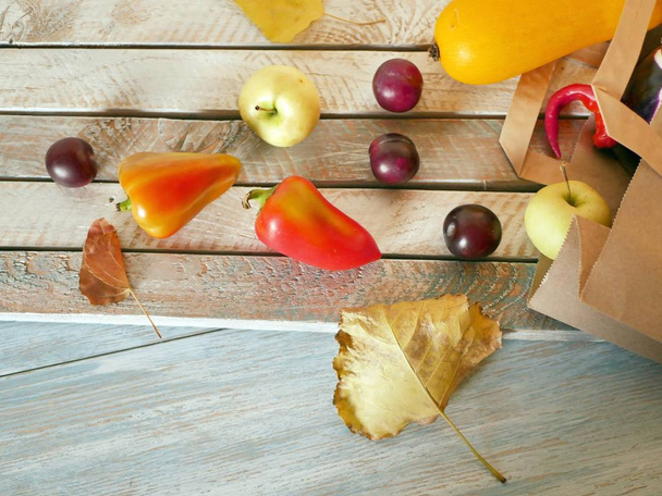 Verdure, frutta, foglie autunnali, un pacchetto dal mercato su uno sfondo leggero in legno, vista dall'alto, il concetto di cibo sano di stagione
 - Foto, immagini