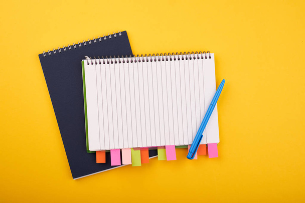 Notizblock mit Farbaufklebern und blauem Stift auf gelbem Hintergrund - Foto, Bild