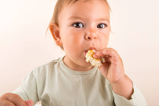 Baby toddler eats food with fingers. Fun face. Copy space - Foto, Imagem