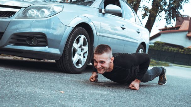 Handsome man near the car. The athlete wrung out next to the machine - Fotoğraf, Görsel