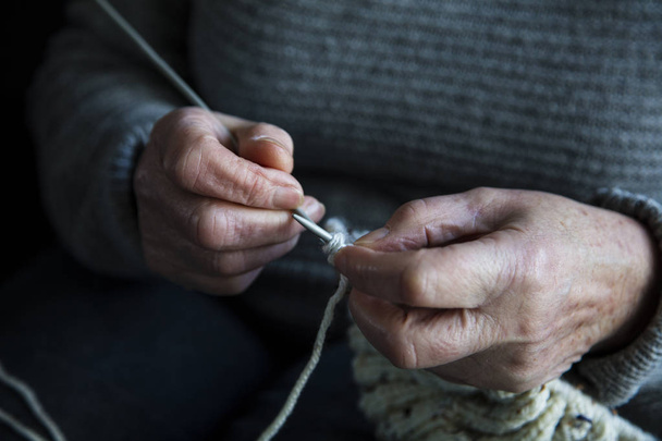 Gros plan d'une femme plus âgée mains tricoter un pull
 - Photo, image