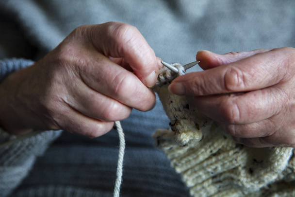 Primer plano de una mujer mayor manos tejiendo un jersey
 - Foto, imagen