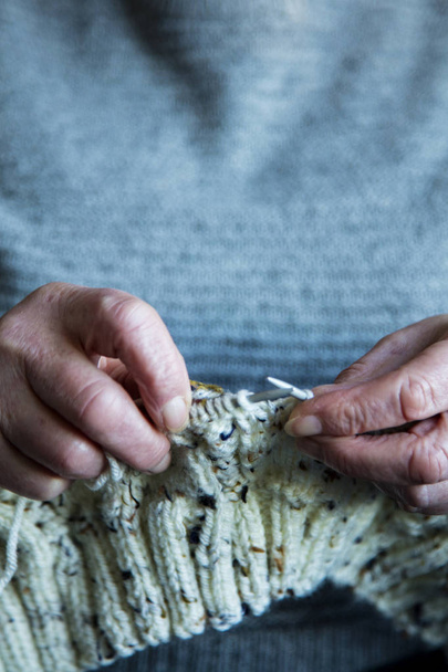 Close up of an older womens hands knitting a jumper - 写真・画像