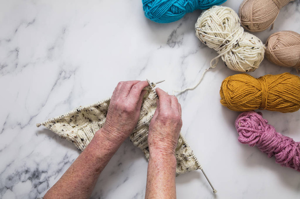 Senoir woman's hands knitting a jumper. Overhead view. - Foto, afbeelding