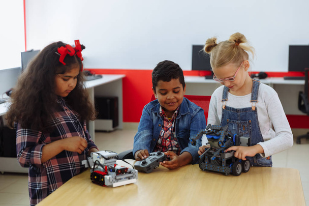 Smíšená rasová skupina tvůrčích dětí pracujících na projektu techniky ve škole. Studentka a dívky hrají a učí se ovládat robota ve třídě. - Fotografie, Obrázek