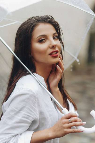 Encantadora joven con paraguas caminando por la ciudad europea. Es lluvia de verano.
. - Foto, imagen