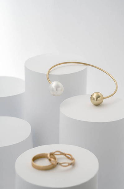 Golden bracelet with pearl on white cylinders and golden rings - 写真・画像