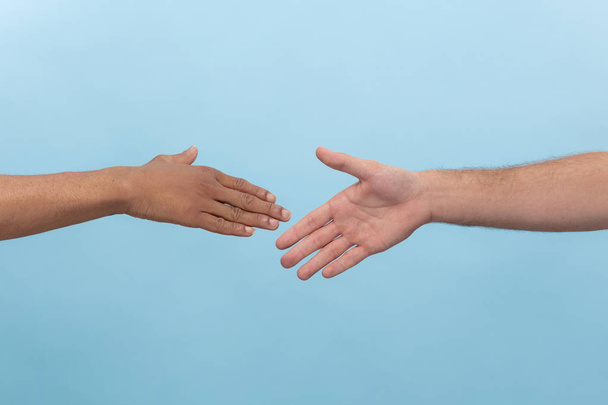 Close up shot of human holding hands isolated on blue studio background. - 写真・画像