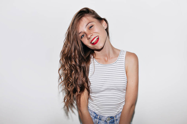 孤立した背景の上に笑顔でカメラを見て赤い唇を持つ長い波状の髪を持つポートレート幸せな女性をクローズアップ - 写真・画像