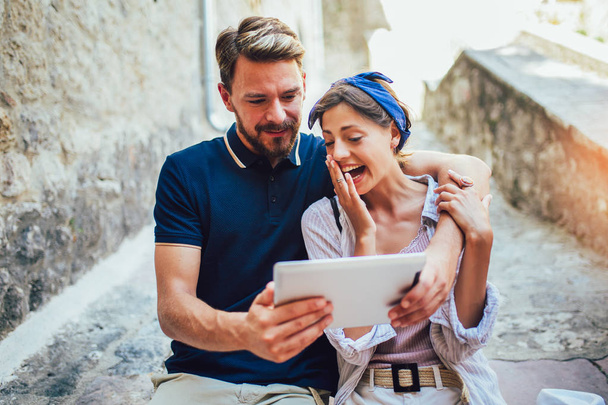 Romantic tourist couple sitting on stairs using digital tablet. - Fotografie, Obrázek