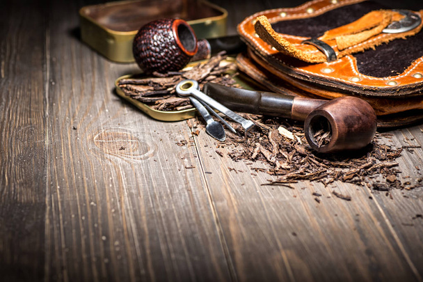 Wooden pipe with tobacco on wooden table. Tin boxes with tobacco - 写真・画像