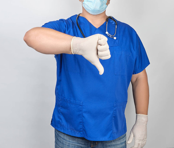 Arzt in blauer Uniform und weißen Latex-Sterilhandschuhen zeigt ein g - Foto, Bild