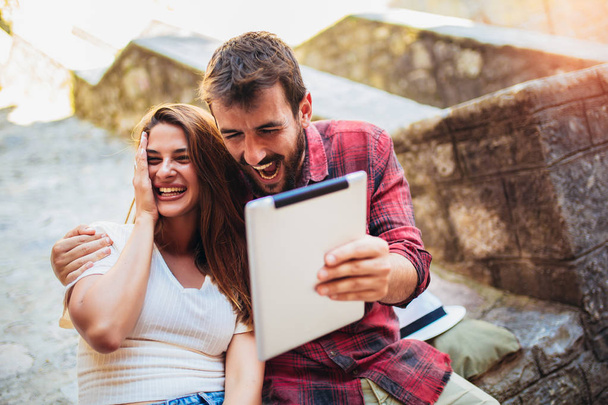 Romantisches Touristenpaar sitzt mit digitalem Tablet auf Treppe. - Foto, Bild