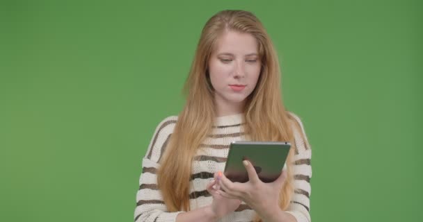 Closeup shoot of young pretty caucasian female using the tablet and showing blue screen to camera - Πλάνα, βίντεο
