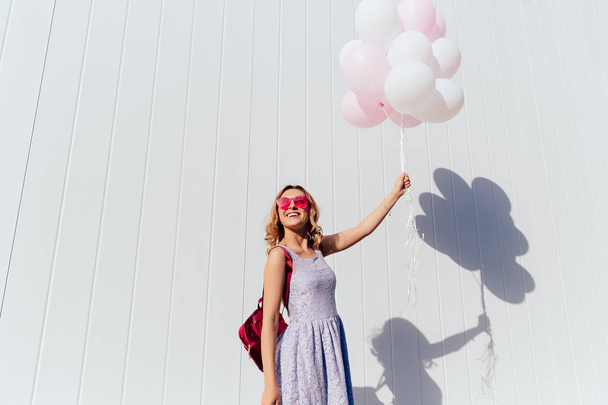 Стильна дівчина розважається з повітряними кулями, на відкритому повітрі
. - Фото, зображення