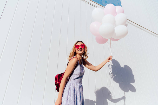 Захоплена дівчина з повітряними кулями, насолоджуючись літніми днями на відкритому повітрі
. - Фото, зображення