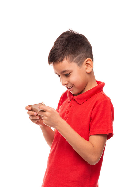 Mladý usměvavý chlapec píše nebo čte SMS nebo hry na  - Fotografie, Obrázek